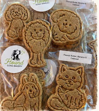 Hand-stamped banana peanut butter oat dog treats shaped like a lion, poodle and cat